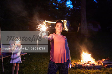 Two girls standing near camp fire, using sparklers