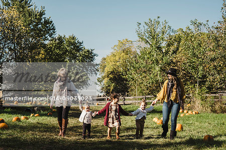 Women and children holding hands in field of pumpkins, Oshawa, Canada, North America