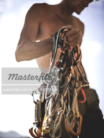 Close up of a climber holding a bundle of rope and carabiners, climbing equipment.