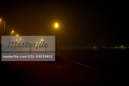 Person walking along deserted waterfront at night
