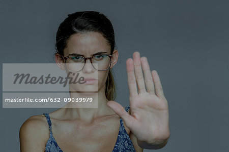 Young woman holding out palm and frowning