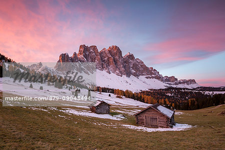Sunrise with two wooden lodges and Odle Dolomites. Malga Gampen, Funes, Bolzano, Trentino Alto Adige - Sudtirol, Italy, Europe.
