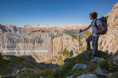 Hikers at Passo del Ciodo admire the panorama to the steep walls of the Third and Fourth Pala. In the background the plateau of the Pale di San Martino. Dolomites, Pale di San Lucano, Agordino, Belluno, Veneto, Italy