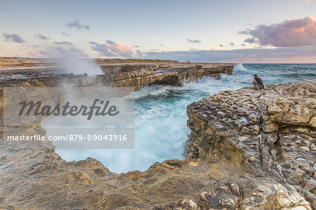 Hiker on the cliffs admires the crashing waves at Devil's Bridge Caribbean Antigua and Barbuda Leeward Islands West Indies Hiker on the cliffs admires the crashing waves at Devil's Bridge Caribbean Antigua and Barbuda Leeward Islands West Indies