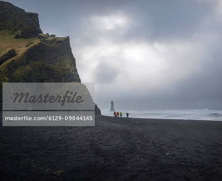 Beach of Reynisfjara, Vik, Sudurland, Iceland, Europe. A group of photographers walks on the black beach.