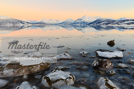 Cloudless sunrise with ice covering the stones on the shore of Balsfjorden. Markenes, Balsfjorden, Lyngen Alps, Troms, Norway, Lapland, Europe.