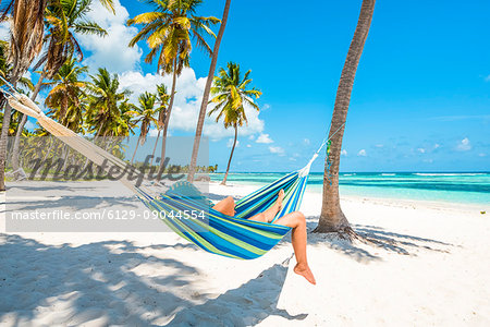Canto de la Playa, Saona Island, East National Park (Parque Nacional del Este), Dominican Republic, Caribbean Sea. Woman relaxing on a hammock on the beach.