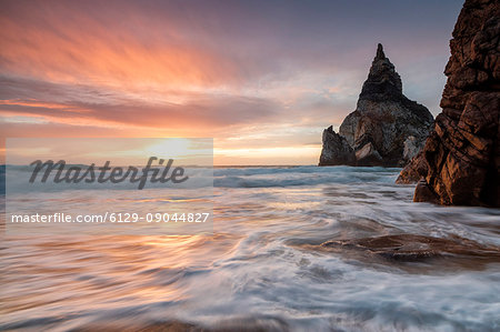 The fiery sky at sunset is reflected on the ocean waves and cliffs Praia da Ursa Cabo da Roca Colares Sintra Portugal Europe