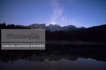 Stars on the peaks of Latemar mountain range reflected in Lake Carezza Ega Valley Province of Bolzano South Tyrol Italy Europe