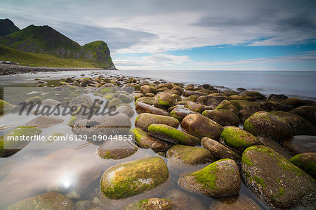 Rocks on the beach frame the calm clear sea Unstad Vestvagøy Lofoten Islands Norway Europe