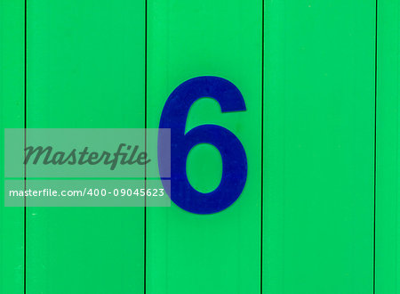 the number six, blue, set against bright green wood