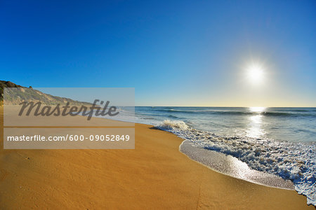 Surf breaking on the shoreline of Ninety Mile Beach at Paradise Beach with the sun shining over the ocean in Victoria, Australia Surf breaking on the shoreline of Ninety Mile Beach at Paradise Beach with the sun shining over the ocean in Victoria, Australia