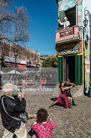 Street tango dancer hamming it up with tourists outside a bar on the corner of El Caminito, La Boca, Buenos Aires, Argentina, South America