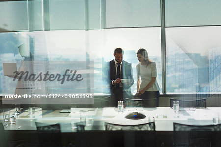 Businessman and businesswoman working, using digital tablet in urban conference room