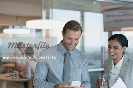 Businessman and businesswoman using cell phone in office