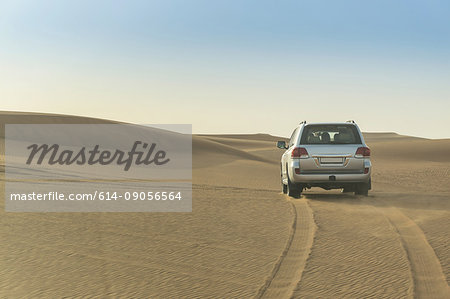 Off road vehicle driving over desert dunes, Dubai, United Arab Emirates