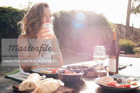 Portrait of young woman, outdoors, sitting at table, holding wine glass