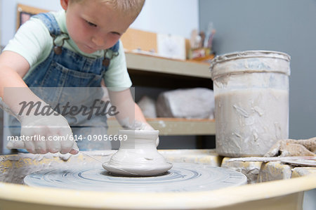 Boy cutting pot from potter's wheel