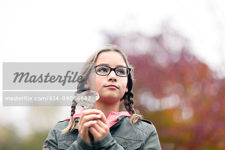 Portrait of girl with plaits and glasses holding leaf