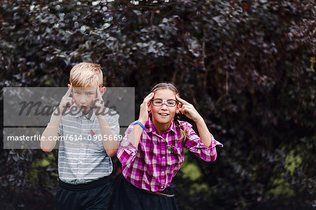 Siblings dressed up as nerds, hands on head looking at camera