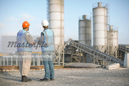 Two quarry workers in discussion, at quarry, rear view