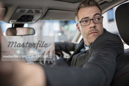 Businessman driving car, looking over shoulder, reversing