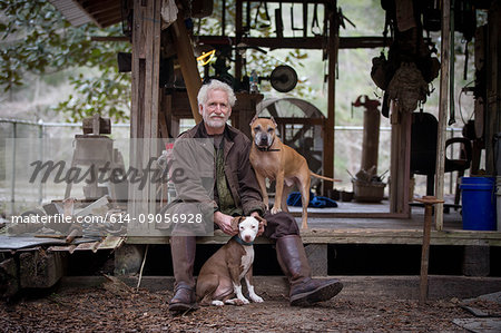 Man with pet dogs by wooden work hut