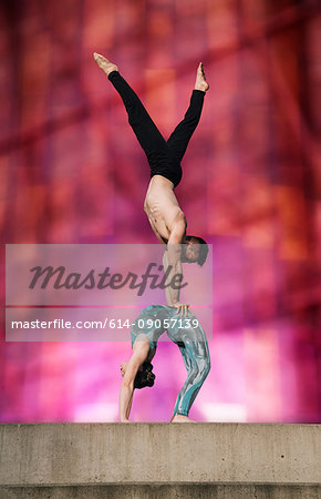 Teenage girl and young man, girl bent backwards in arch, man doing handstand on girls stomach