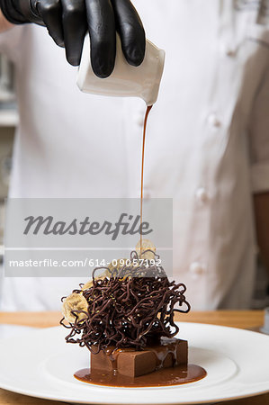 Chef pouring cream over chocolate nest cake decoration on cake