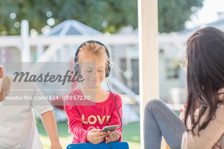 Young girl holding smartphone, wearing headphones