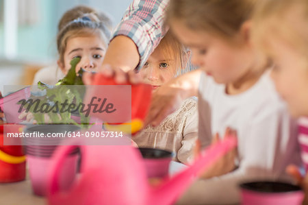 Woman helping young children with gardening activity