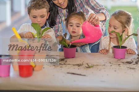 Mid adult woman helping young children with gardening activity