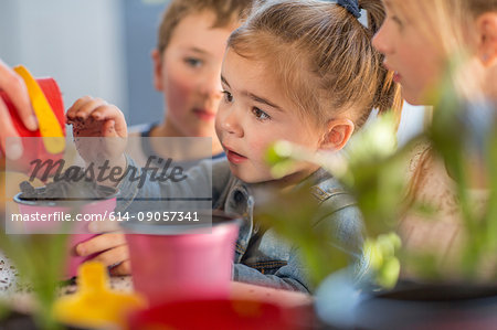 Mid adult woman helping young children with gardening activity, close-up