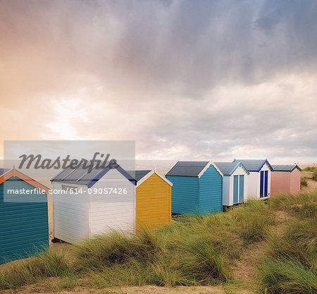 Row of colourful beach huts and storm clouds over sea, Southwold, Suffolk, England