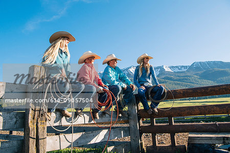 Cowboys and cowgirls on fence, looking away, Enterprise, Oregon, United States, North America