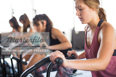 Young woman using elliptical bike in exercise class