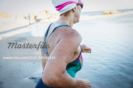 Female open water swimmer running into ocean