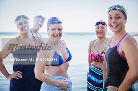 Portrait smiling, confident female open water swimmers drying off with towels at ocean