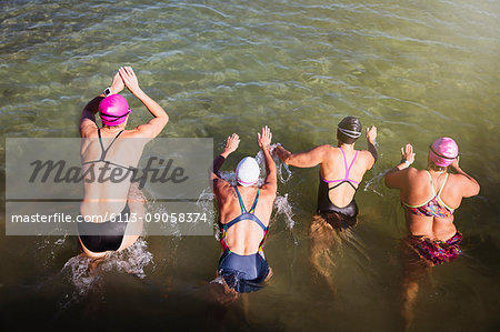 Overhead view female open water swimmers swimming in sunny ocean