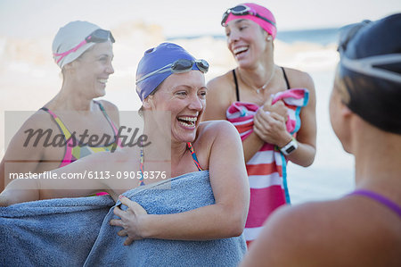 Laughing female open water swimmers drying off with towels