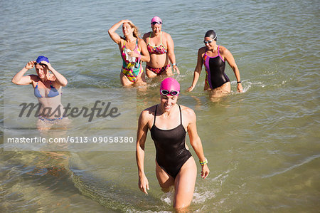Overhead view female open water swimmers wading in sunny ocean