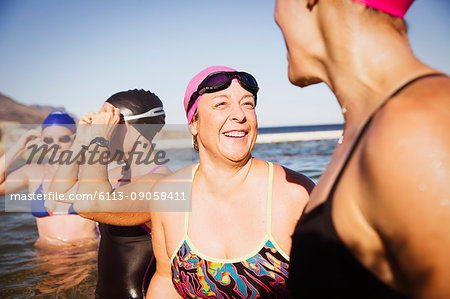 Laughing female open water swimmers talking in sunny ocean Laughing female open water swimmers talking in sunny ocean