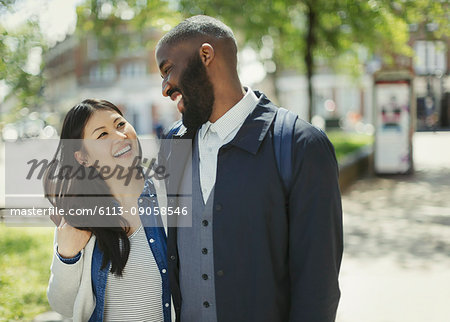 Affectionate couple laughing in sunny urban park