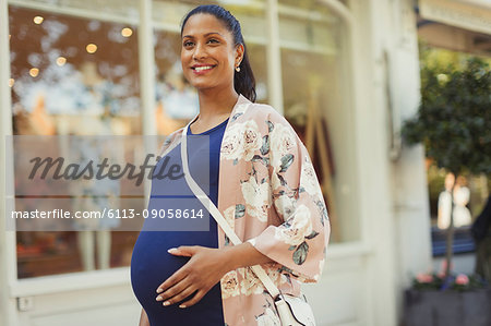 Portrait smiling pregnant woman outside storefront