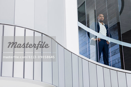 Confident CEO businessman standing in modern office window