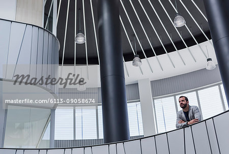 Pensive businessman on architectural, modern atrium balcony