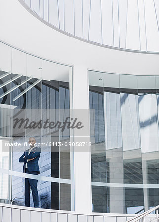Portrait confident, serious CEO businessman standing at modern office window