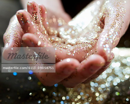 Close up hands cupping gold glitter