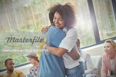 Smiling woman hugging man in group therapy session