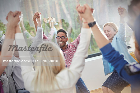 People smiling and holding hands in circle in group therapy session